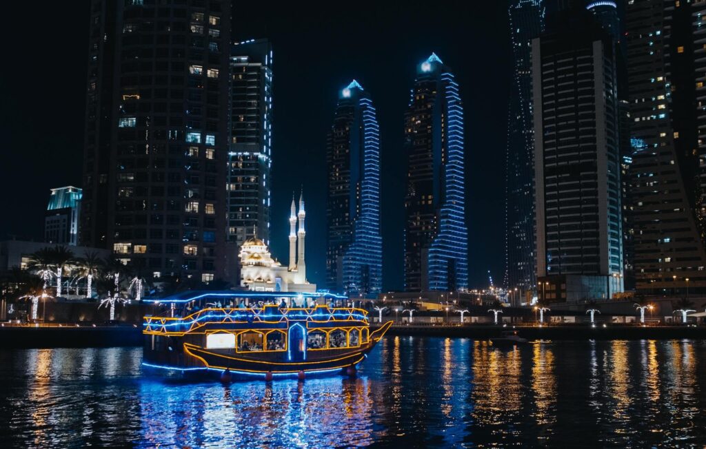 a boat in the water with lights which we can say "Dhow Cruise"