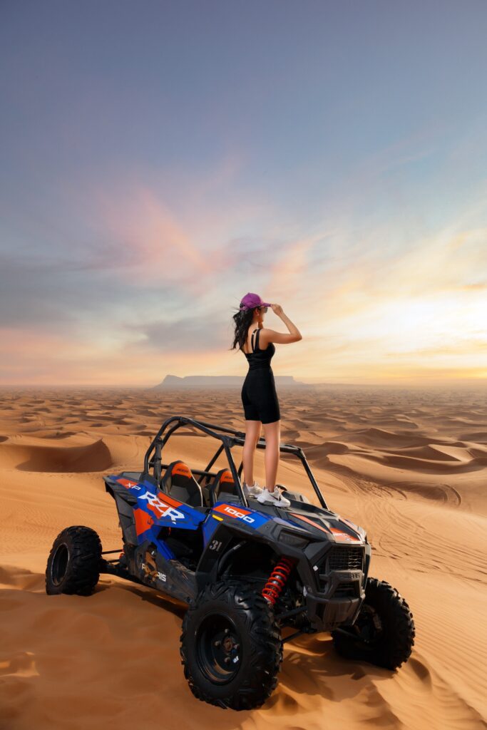 a girl standing on a vehicle in the desert